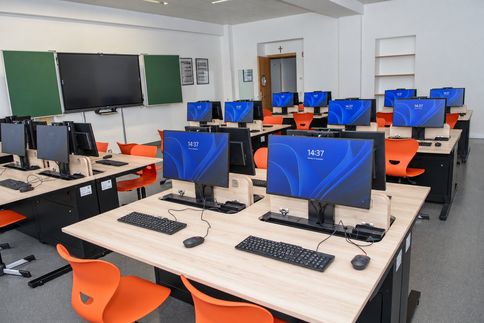 Computerraum der Ecole Privée Fieldgen mit Tafel, Display und Tischreihen mit ausgefahrenen Monitoren