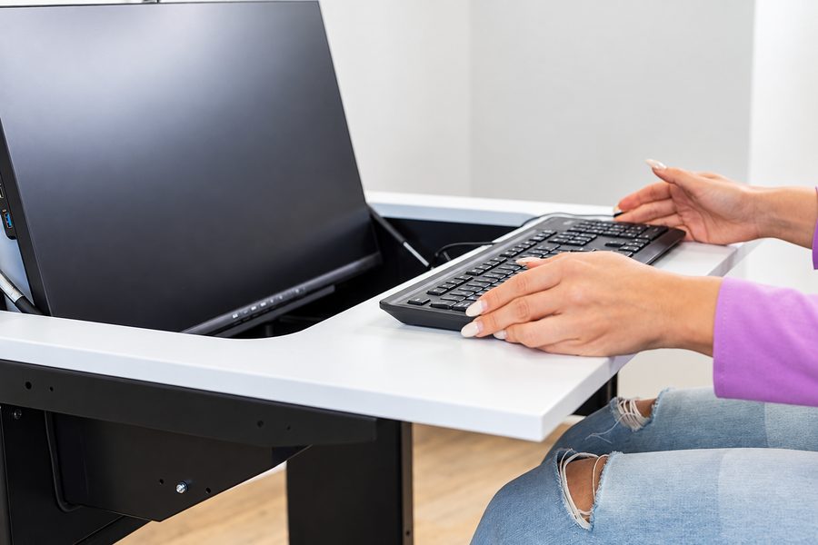 Arbeitsplatz am Tisch mit ausgefahrenem Monitor, Tastatur auf der Tischplatte