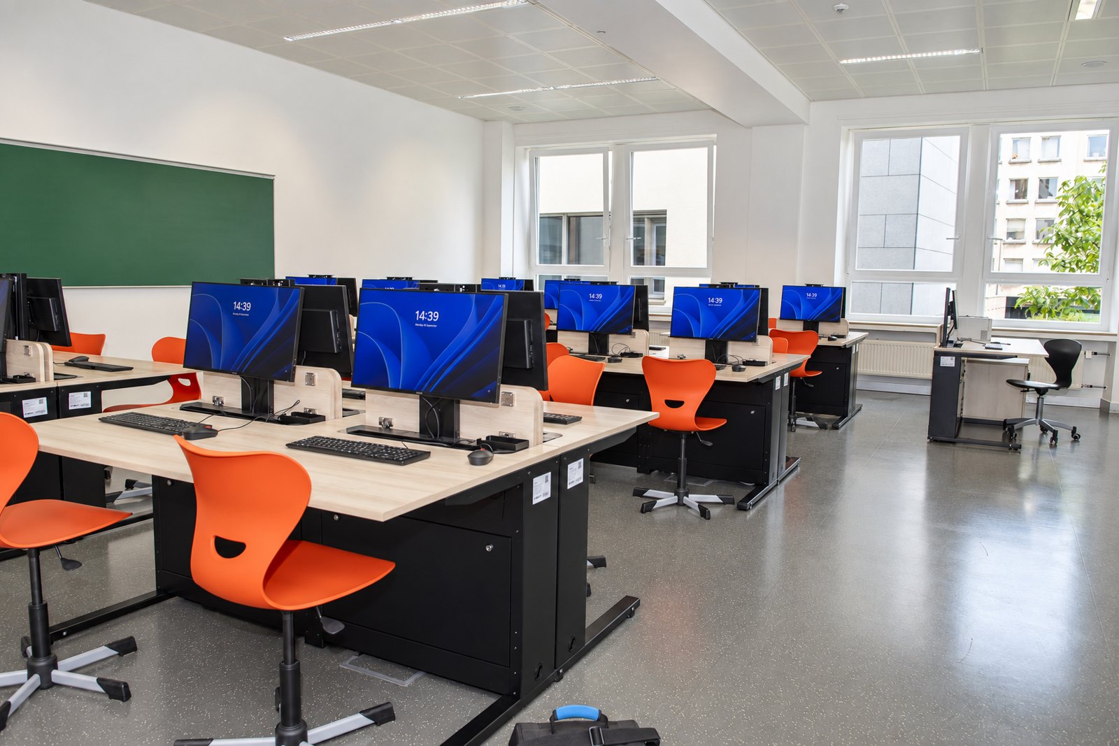 Heller Unterrichtsraum der Ecole Privée Fieldgen mit Tischen mit versenkbaren Monitoren und Fensterfront