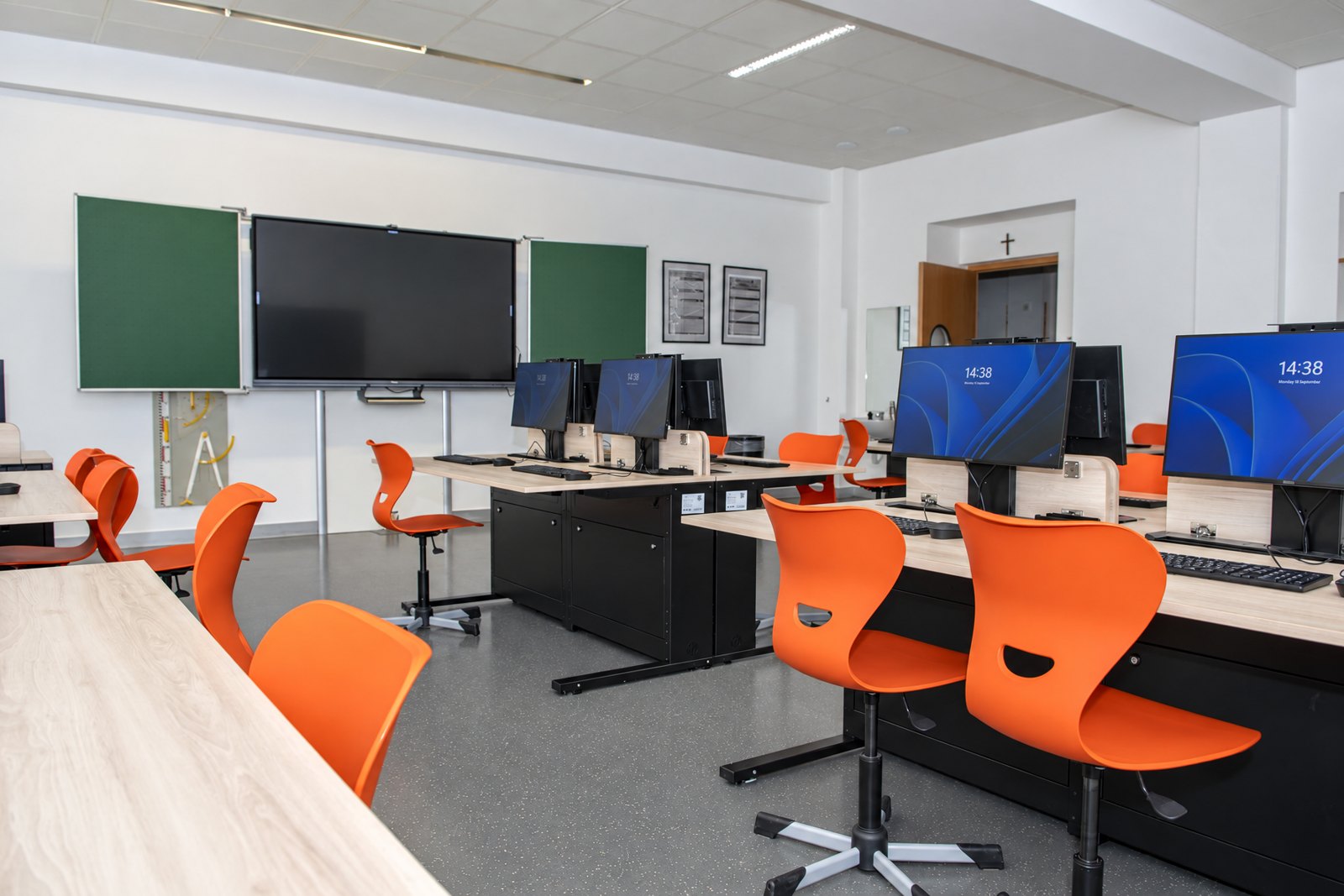Unterrichtsraum der Ecole Privée Fieldgen mit Tafel, Display und Tischreihen mit ausgefahrenen Monitoren